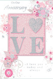 This anniversary card presents a gentle tribute to enduring romance, blending pale pastel pinks, soft mauves, and cool silvery greys into a design that feels both intimate and refined, much like a cosy dinner in a Putney flat after a walk along the Embankment. At the heart of the card, the word LOVE is arranged in softly raised glitter, each letter glimmering under the light. The O is replaced by a textured heart, filled with shimmering silver that stands out like a special blossom in the centre of a carefully curated bouquet. Around this focal point, delicate blooms unfold in blush and mauve, their edges and shading reminiscent of watercolour strokes, with petals that appear to blur gently into the background. Fine, flowing lines trace slender stems and curling vines, linking each flower in a fluid rhythm. Tiny flourishes-petals, spirals, and subtle butterfly shapes-add movement, suggesting the graceful flutter you might feel when receiving a surprise anniversary gift. The background is a soft, powdery pink that brightens toward the centre, enhancing the sense that the floral and heart motif is gently glowing. Above and below, the sentiments On Our Anniversary and I love you today and always are written in an elegant script, the lettering narrow and slightly curved, echoing the organic lines of the floral design. Nothing appears crowded; there is generous space around each element, giving the card a quiet, considered beauty. The overall effect is like an English spring garden translated into paper, ideal for pairing with fresh anniversary flowers delivered to homes across Putney, from the high street to the leafy avenues beyond.